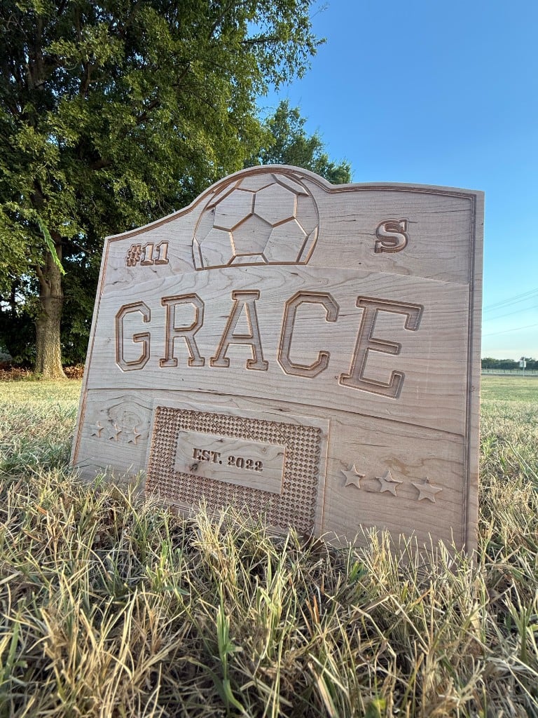 Carved wooden sign reading Grace, with a soccer ball, number 11, and EST. 2022.